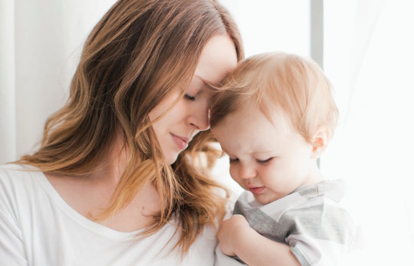 Madre abrazando a su bebé con los ojos cerrados