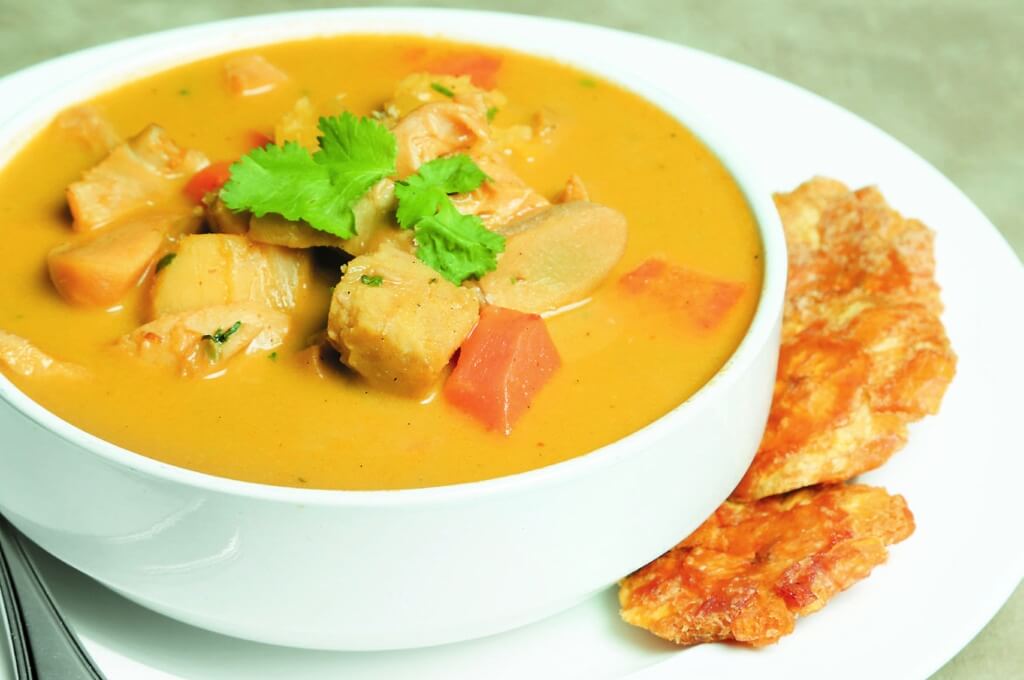 Sopa de frijoles con verduras y tostones en un plato blanco.