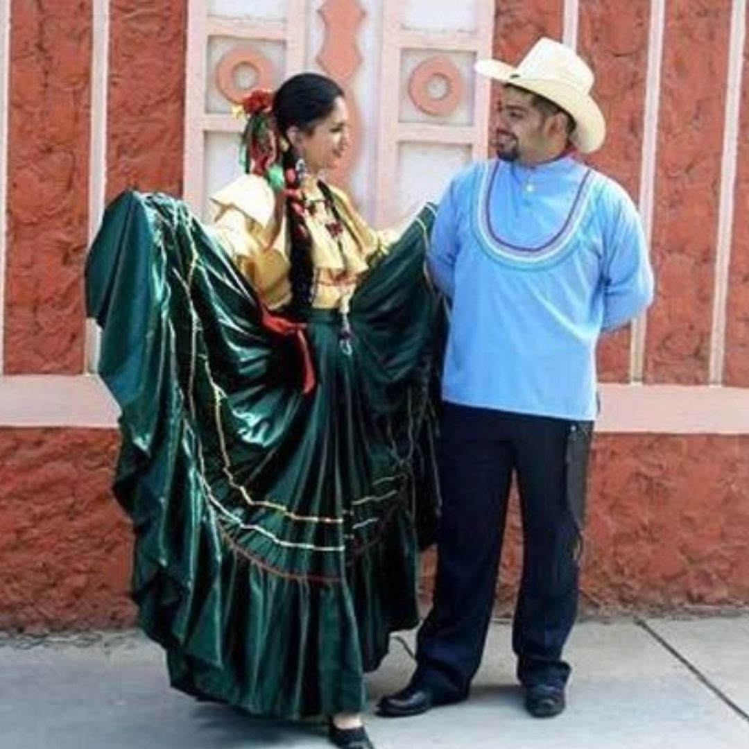 Traje típico de mujer amarillo y verde y traje de varón con camisa azul y pantalón negro.