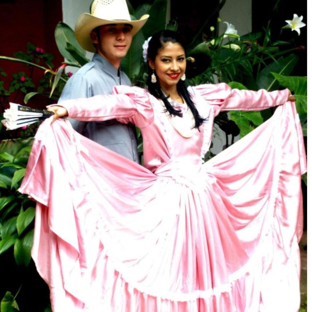 Mujer con vestido rosado y encaje blanco y hombre con traje gris.