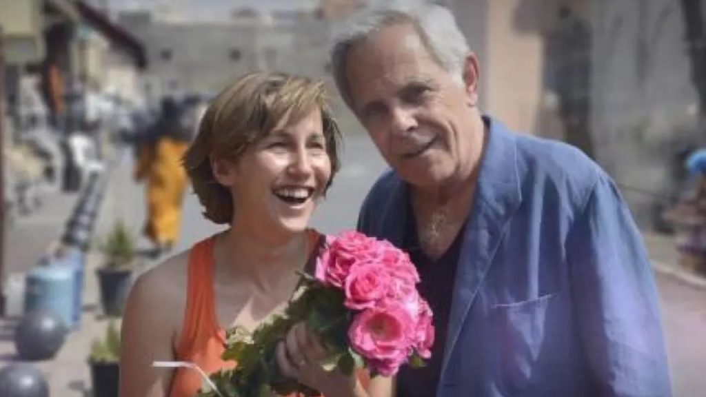 Sandra sonriendo con una ramo de flores al lado de Giménez.
