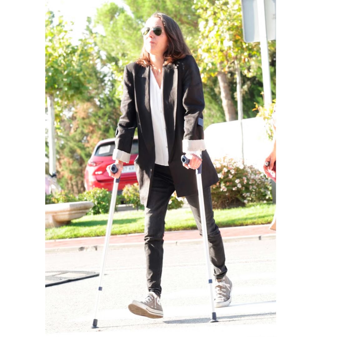 Foto en alta calidad de de Sandra Salgado caminando con muletas y ropa negra.
