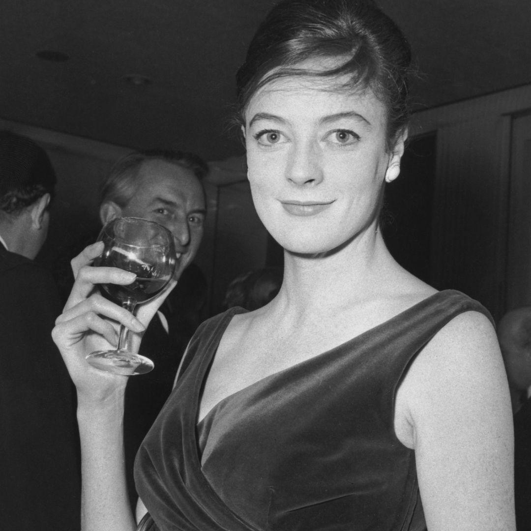 Smith años atrás con vestido de gala negro y una copa de vino.