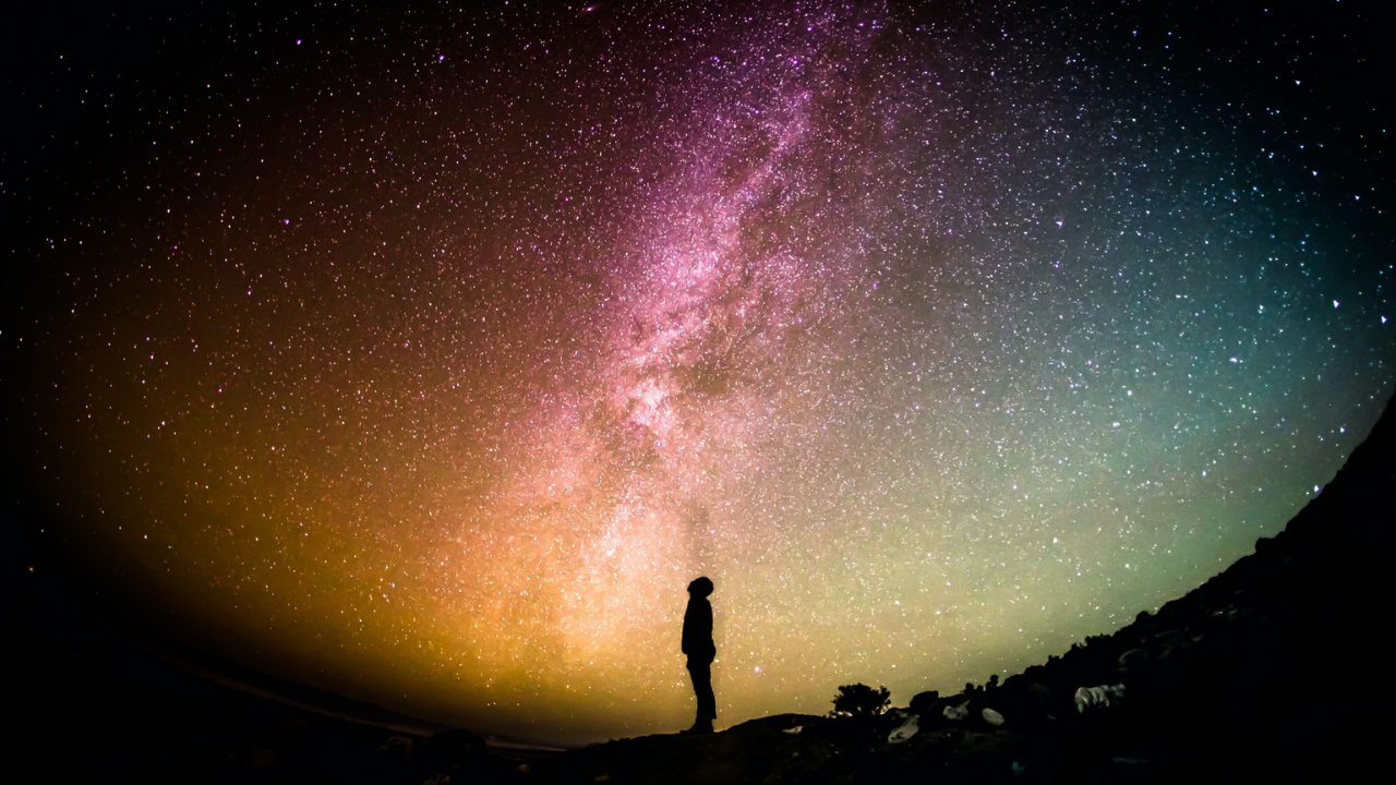 El cielo estrellado con varios colores, entre verde, rosado y anaranjado.