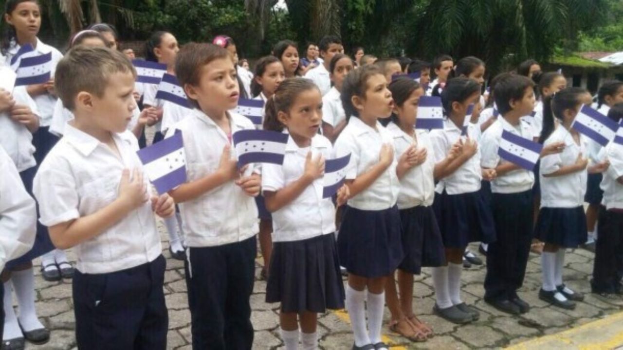 Niños cantando el Himno Nacional de Honduras con banderitas