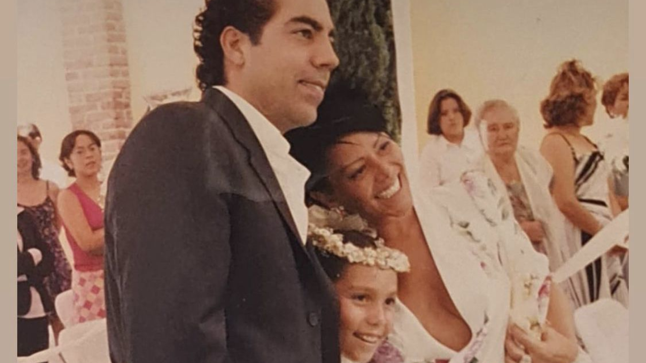 Pablo Moctezuma con traje formal blanco y negro y Alejandra Guzmán con vestido blanco y flores rosadas. 