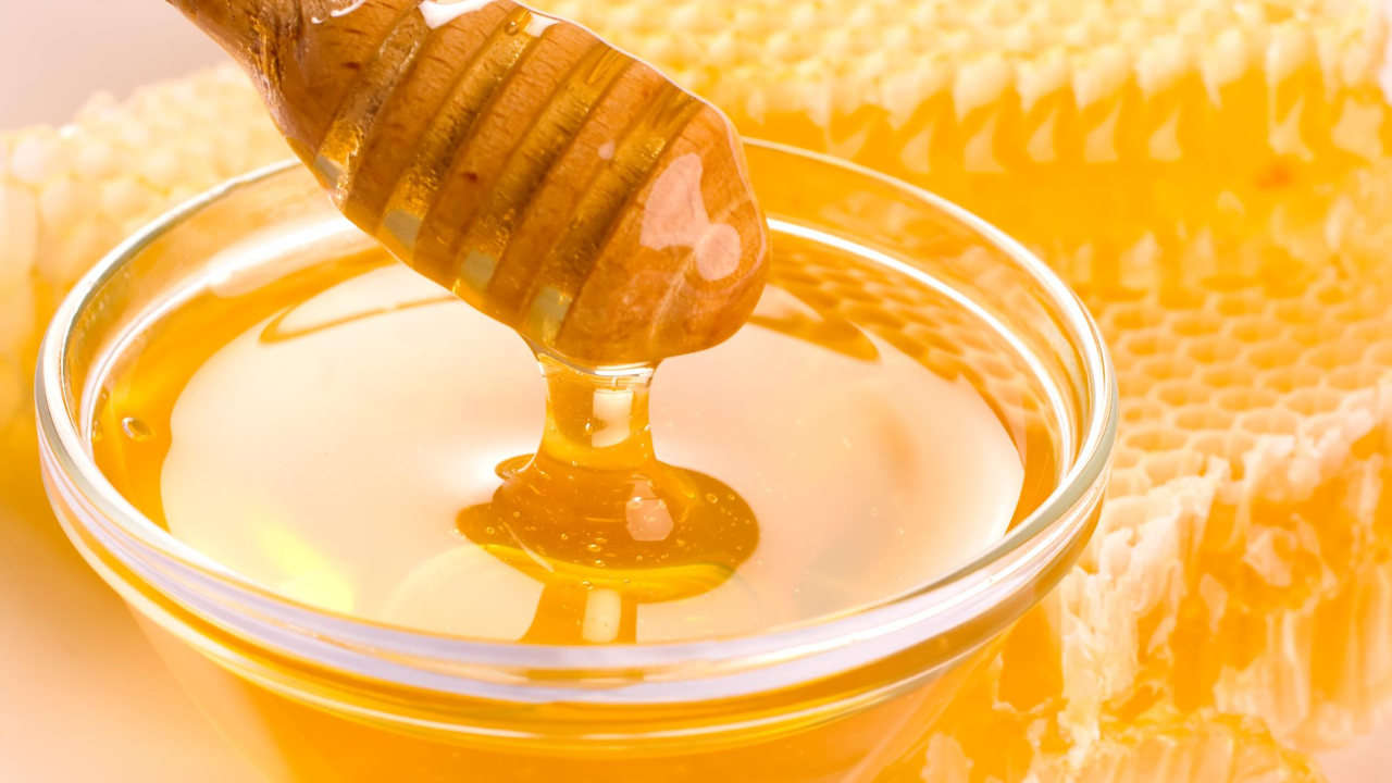 Miel de abeja color amarillo medio claro en una taza de cristal.