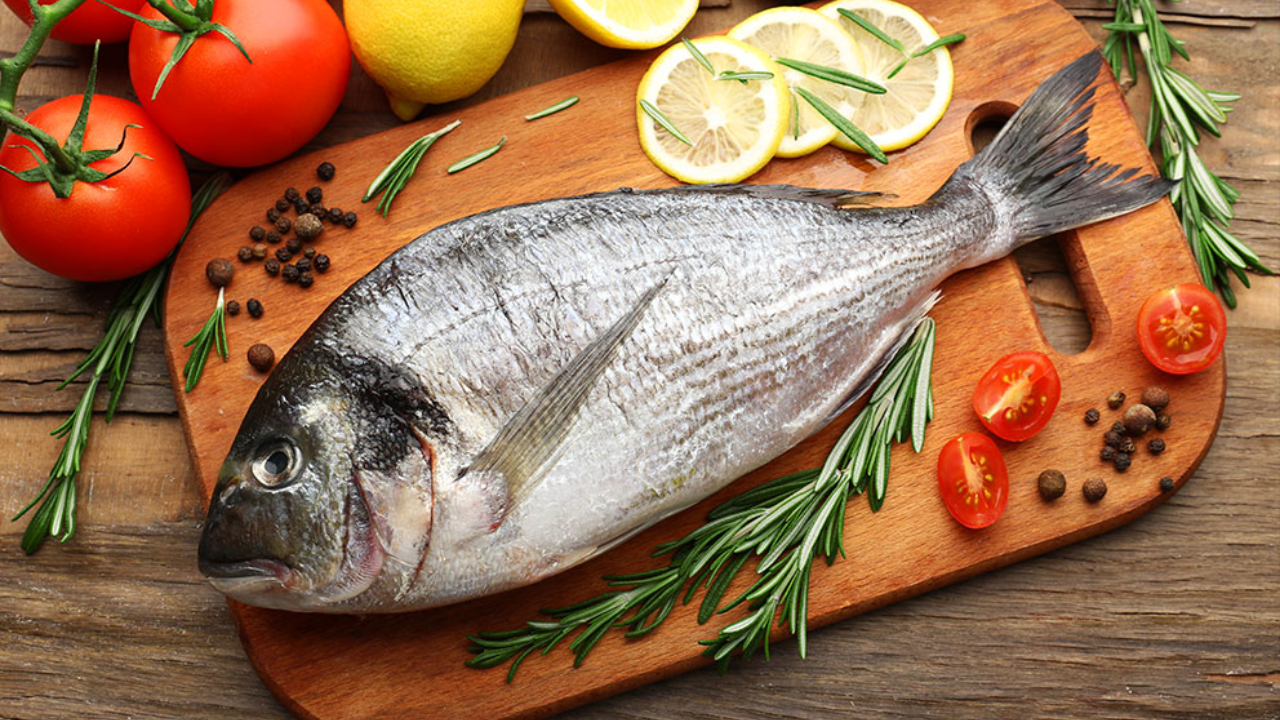 Un pescado color gris en una tabla de picar. 