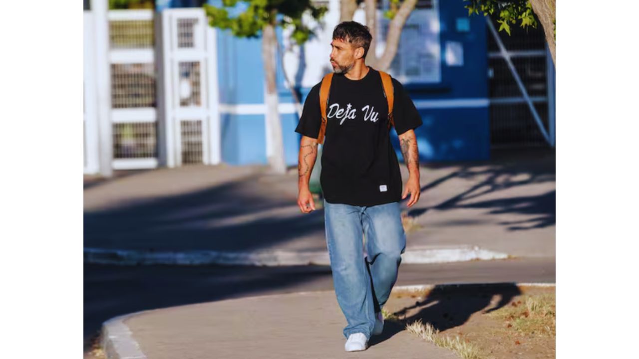 Foto de Jorge Valdivia caminando por la calle con camisa color negro y pantalón jeans color azul claro.