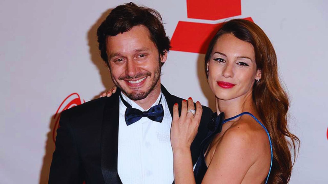 Foto de Benjamín exparejas, vestido de traje formal color blanco y negro, junto a Pampita con vestido color azul.