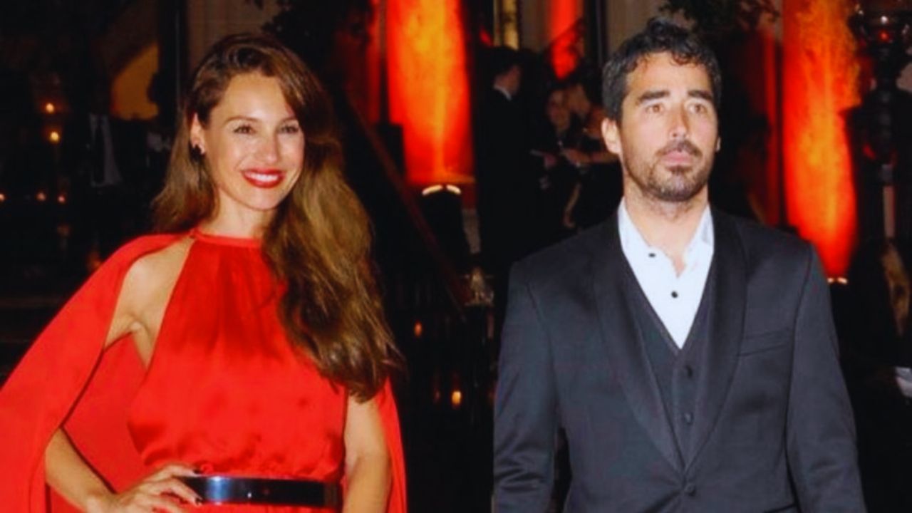 Foto de Pampita vestida de rojo y Nacho, vestido con traje formal color blanco y negro.