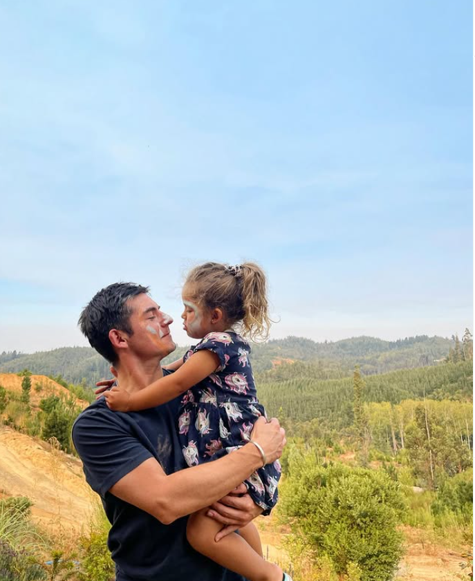 Claudio Castellón con su hija en el bosque utilizando camisa negra