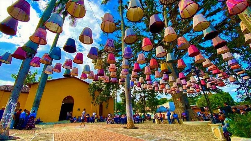 Al fondo iglesia, parte alta lamparas de colores hecha de telares lencas