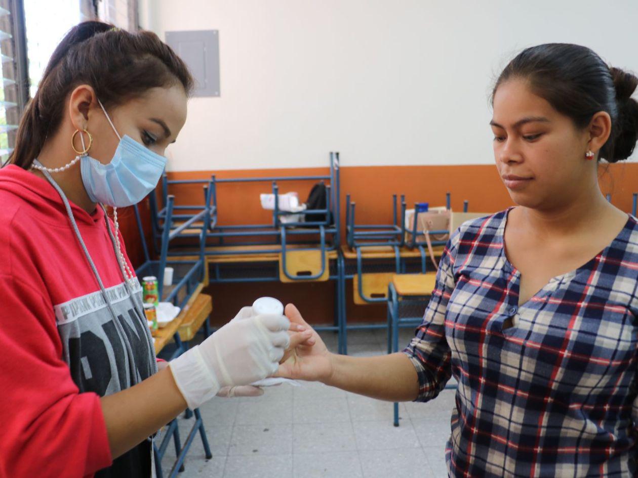 Una joven marcando el dedo de una ciudadana después de votar.