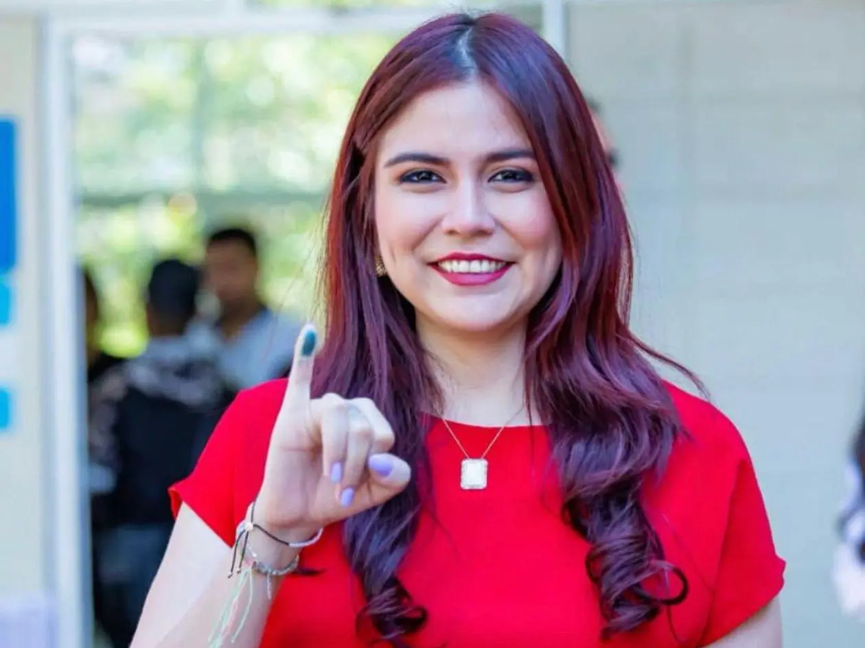 Haydee López Flores con camisa roja y mostrando su dedo meñique de votación 