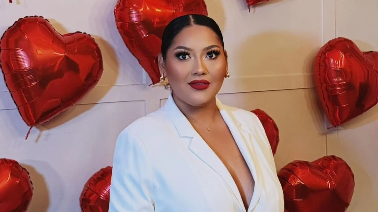 Dayssi89 con un blazer blanco y globos de corazón en el fondo.