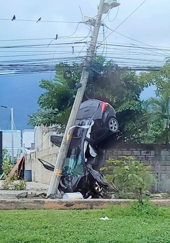 Contra todo pronóstico, el carro quedó 'ensartado' de forma vertical entre el poste y el muro.