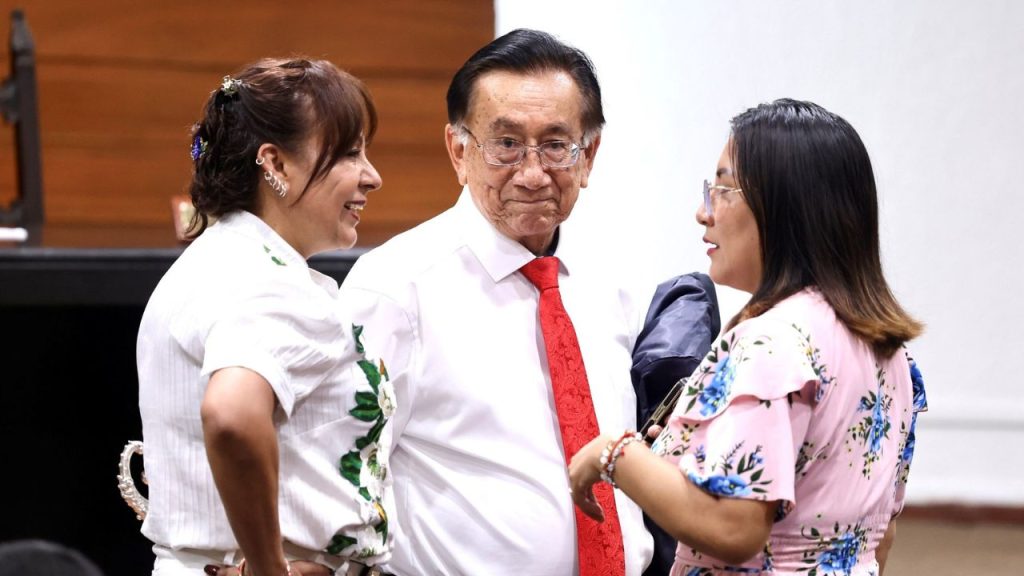José María Balcázar vestido de camisa de botones blanca y corbata roja.