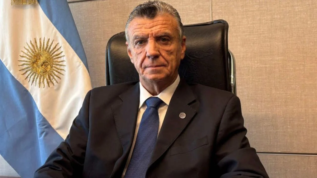 Mario Grinman sentado junto a la bandera de Argentina.