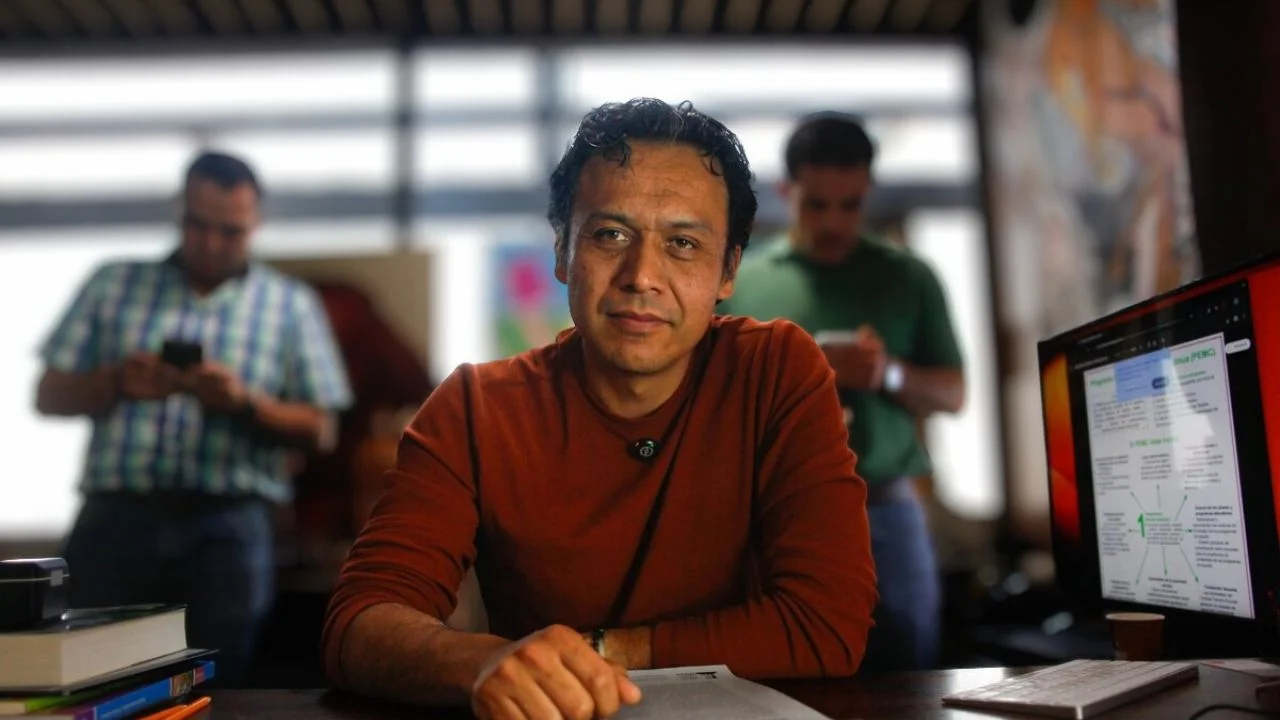 Max Arriaga con un suéter rojo desde su oficina.