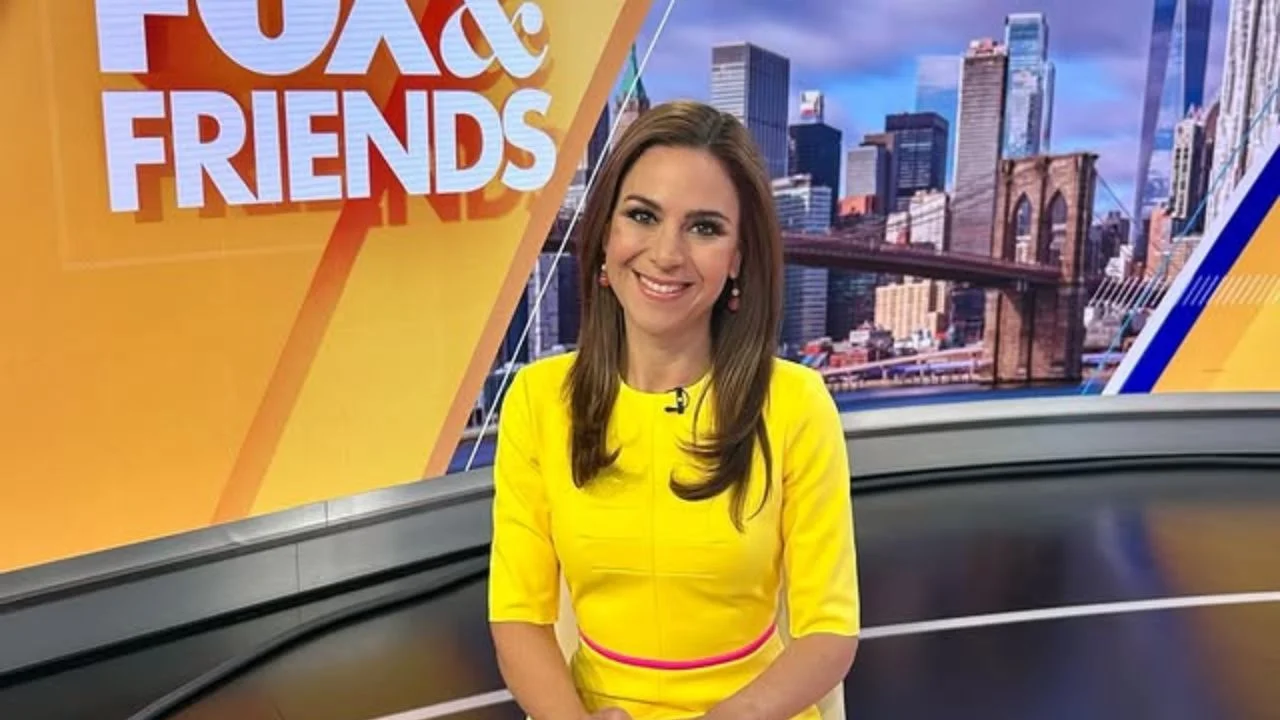 Jackie DeAngelis con un vestido amarillo en un set de televisión.
