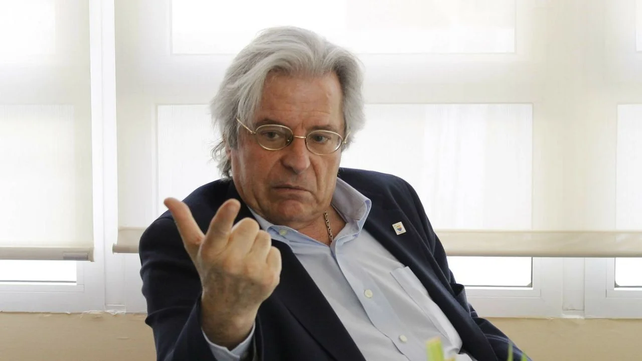 Javier Nart con saco y camisa de botones haciendo una seña a la cámara.