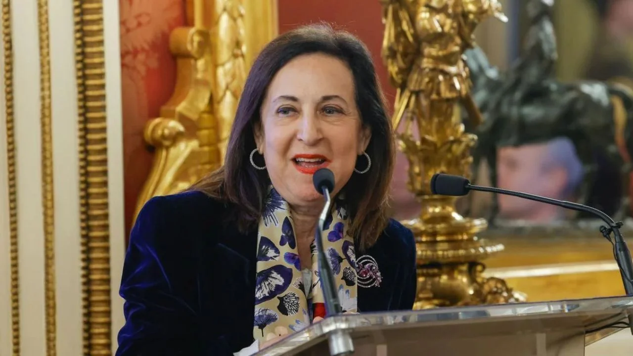Margarita Robles con un blazer negro hablando a un micrófono.