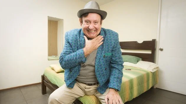 Tulio Loza con sombrero y tocándose el cuello con la mano derecha