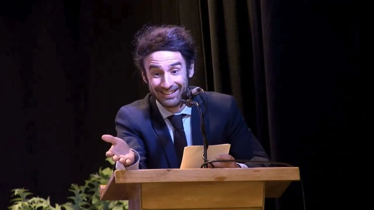 Antonini de Jiménez de saco y corbata en un estrado con un micrófono.