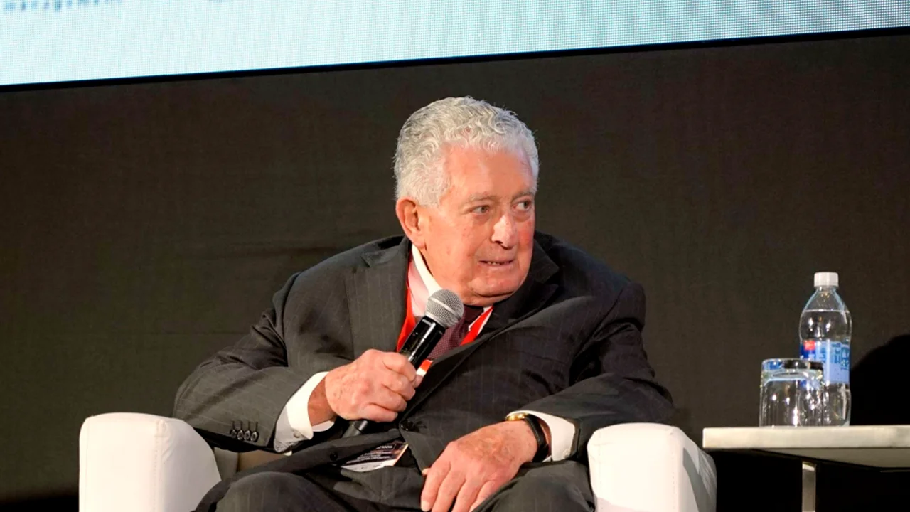 Óscar González Rocha sentado con un micrófono en mano.