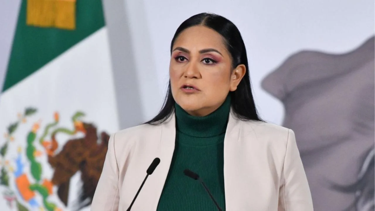 Ariadna Montiel con un blazer blanco y blusa verde frente a un podio.