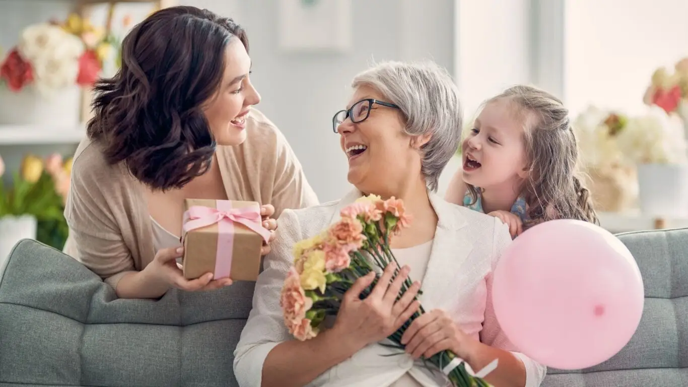 Foto de una madre, hija y nieta dando regalos por el Día de la Madre