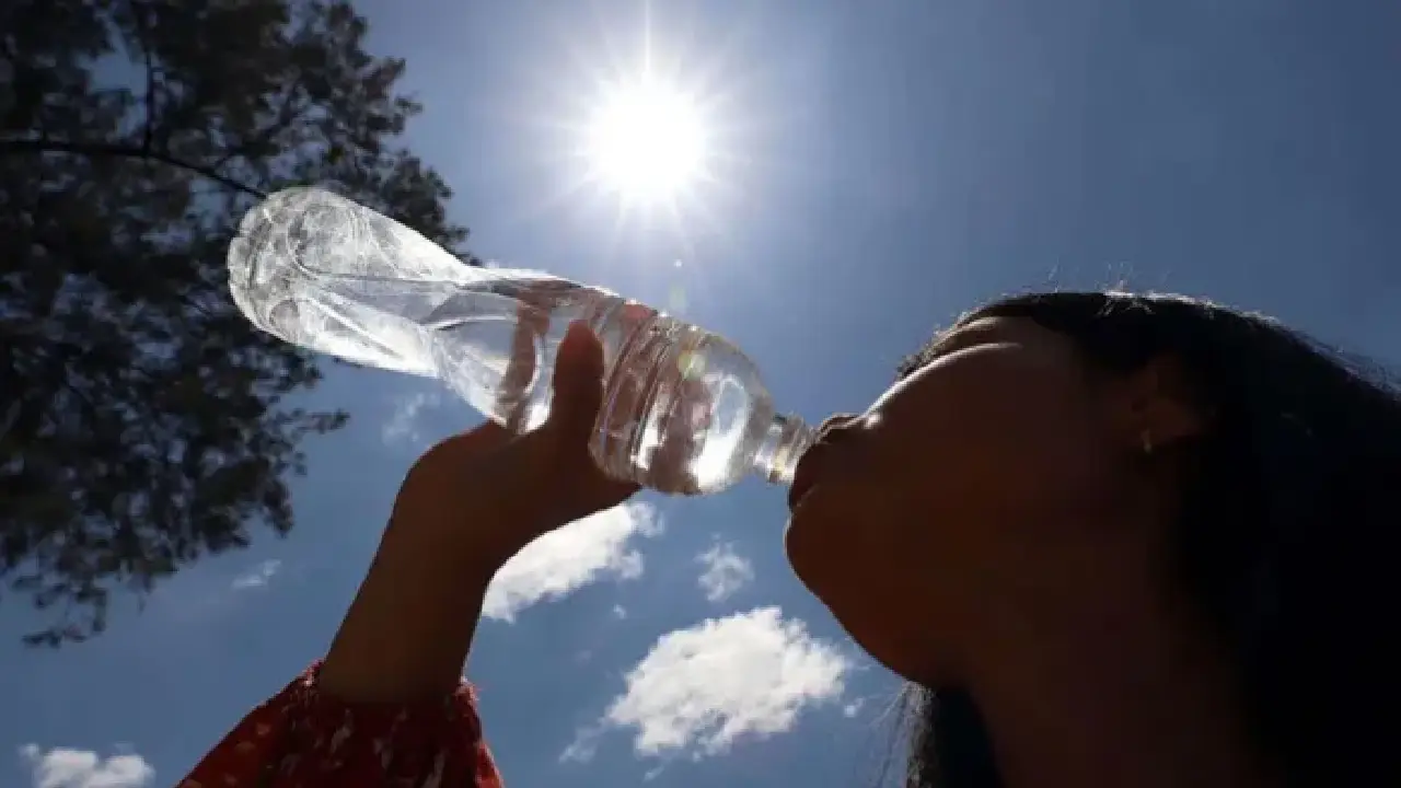 Una mujer toma agua mientras se expone a un sol intenso