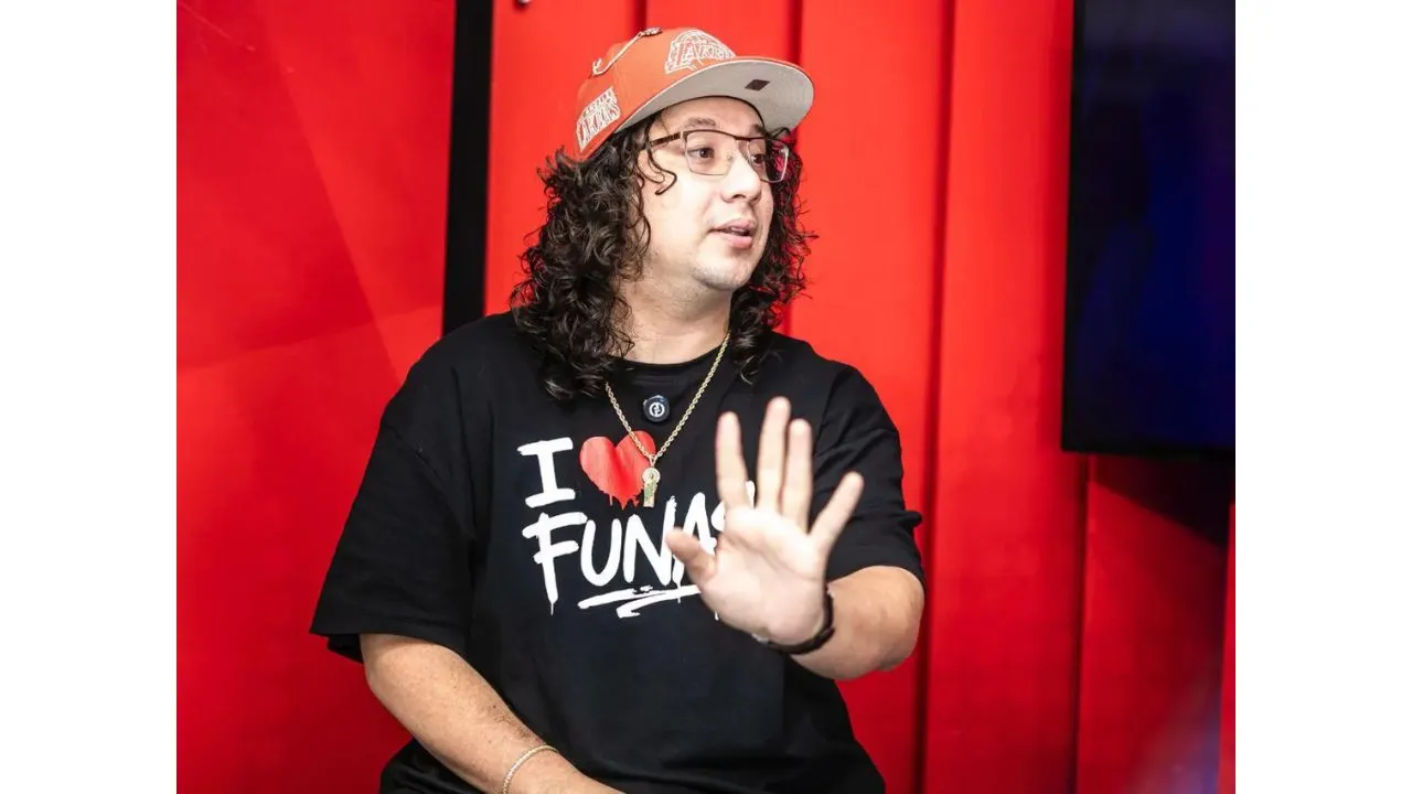Alan extiende su mano y posa con una gorra color naranja.