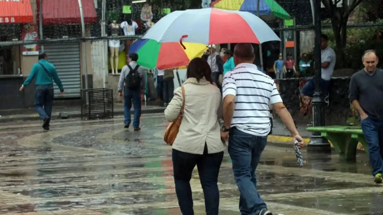 Una pareja se cubre de la lluvia con una sombrilla.
