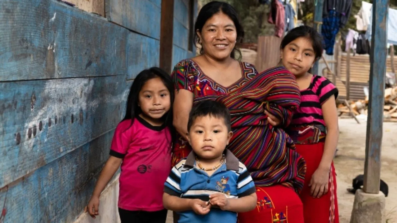 Una madre guatemalteca con sus hijos en una casa humilde.