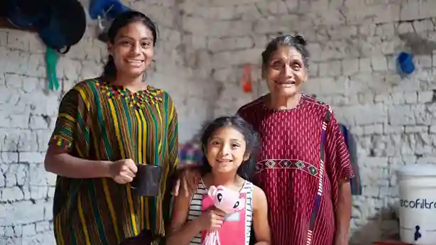 Una madre, abuela e hija juntas en una fotografía ubicadas en una casa de Guatemala todas con una sonrisa.