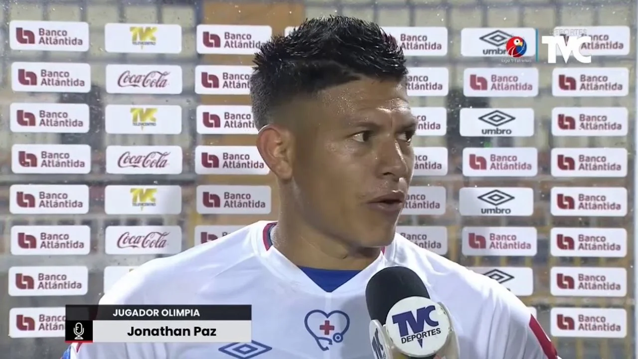 Jonathan Paz con su traje deportivo a la par de un micrófono dando una entrevista a Deportes TVC