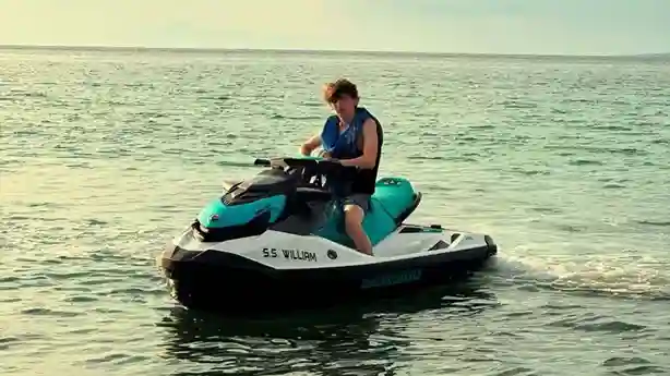 Lorenzo con un chaleco azul conduce una moto acuática sobre el mar. 