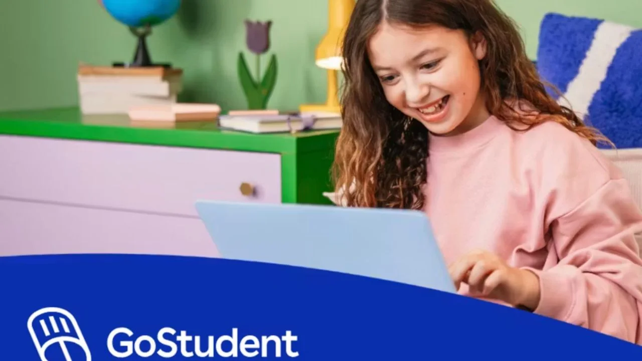 Niña con su computadora en la mano disfruta de los videos interactivos de aprendizaje en inglés.
