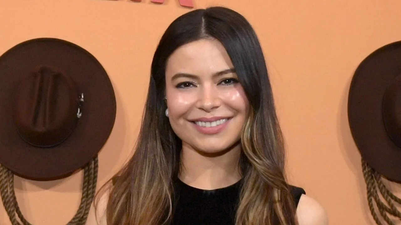 Miranda Cosgrove con un vestido negro en una pasarela.