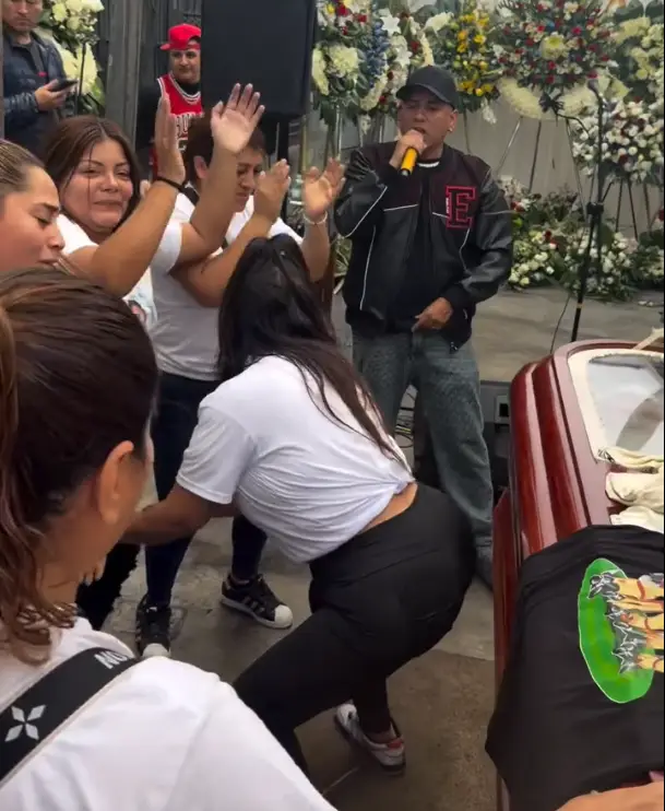Mujer porreándole al ataúd de su esposo