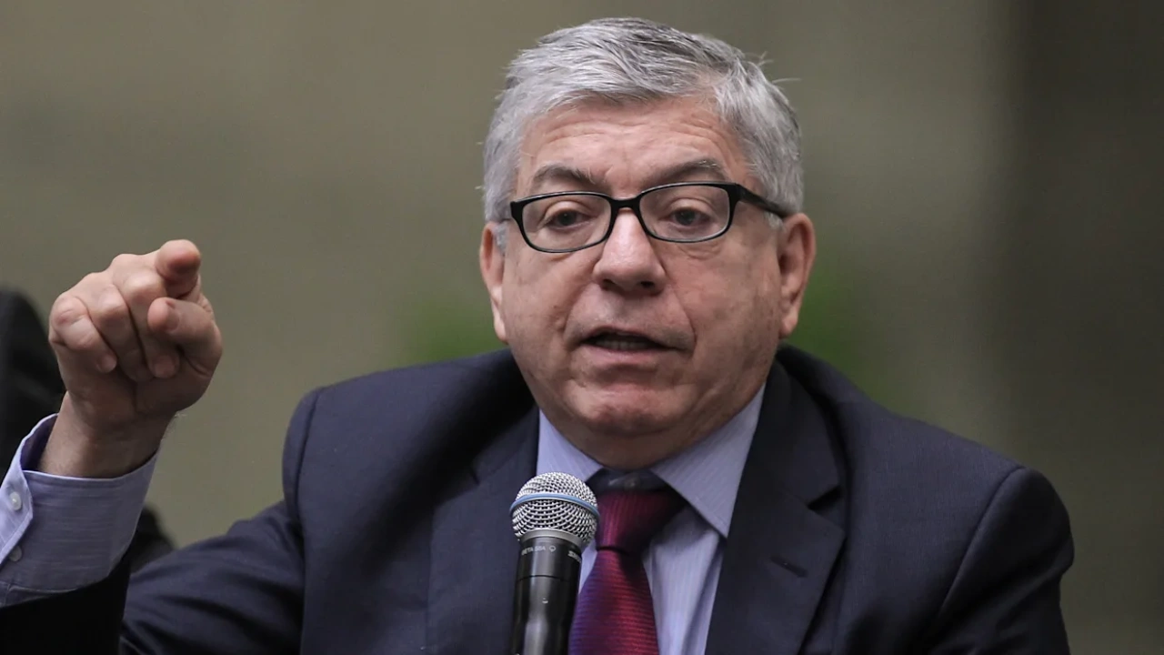 César Gaviria con lentes, saco azul, camisa azul y corbata roja.