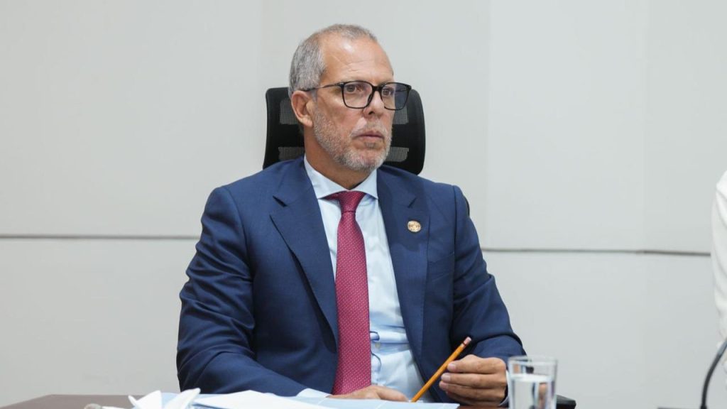 Alfredo Saade sentado y vestido de saco azul, camisa celeste y corbata roja.
