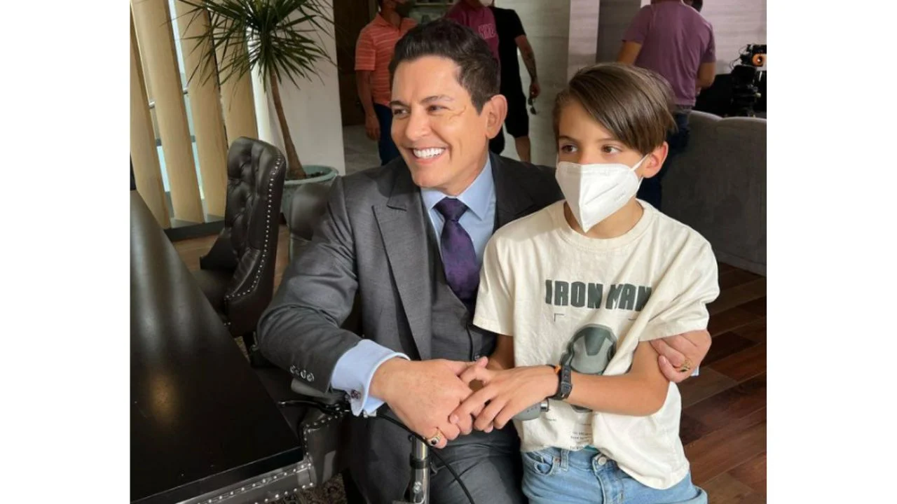 Emiliano con una mascarilla blanca puesta mientras lo abraza su padre Ernesto.