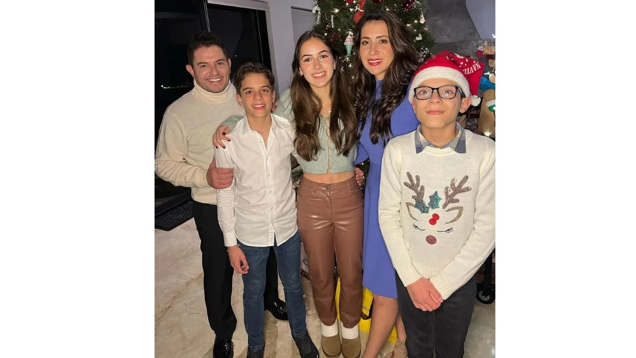 Ernesto y sus hijos de pie abrazados en una celebración con su esposa.