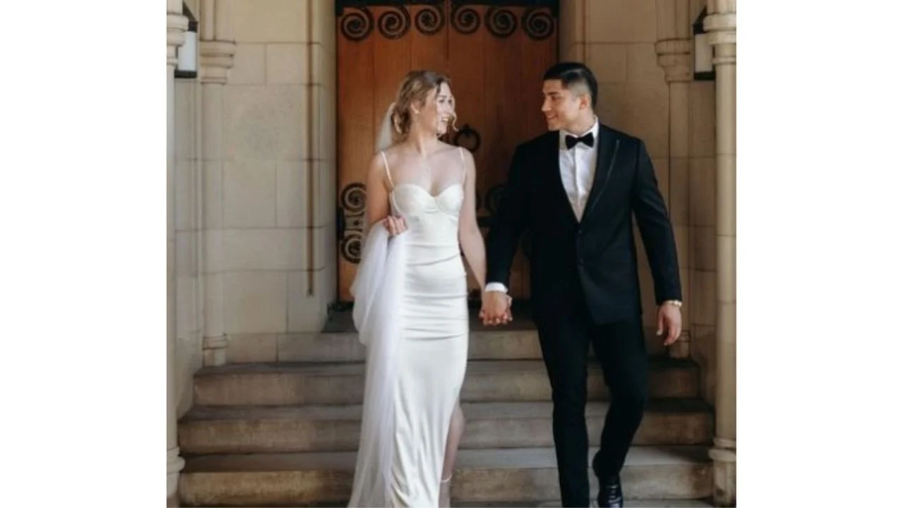 Carlos y Sondra tomados de la mano y vestidos de novio y novia en su matrimonio.
