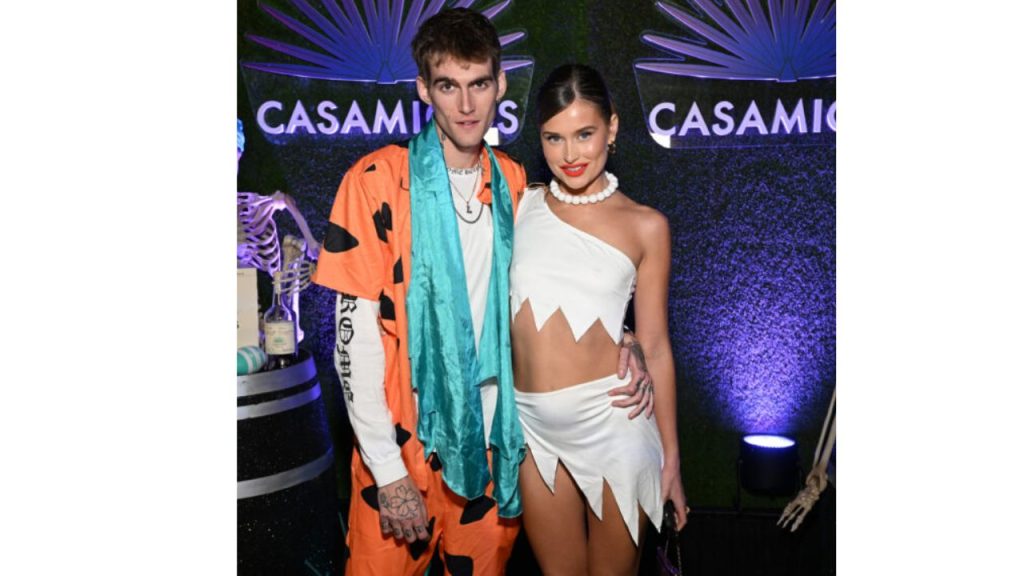 Presley con su ex novia en un evento donde lucen trajes de colores naranja y blanco.