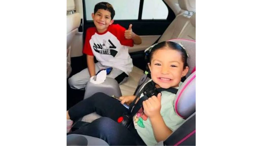 Hijos de Esparza sonríen y posan mientras están en un carro.