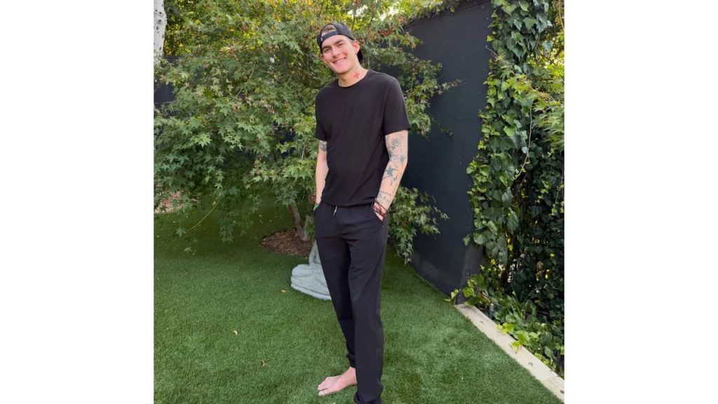 Presley posa descalzo en área verde para una fotografía.